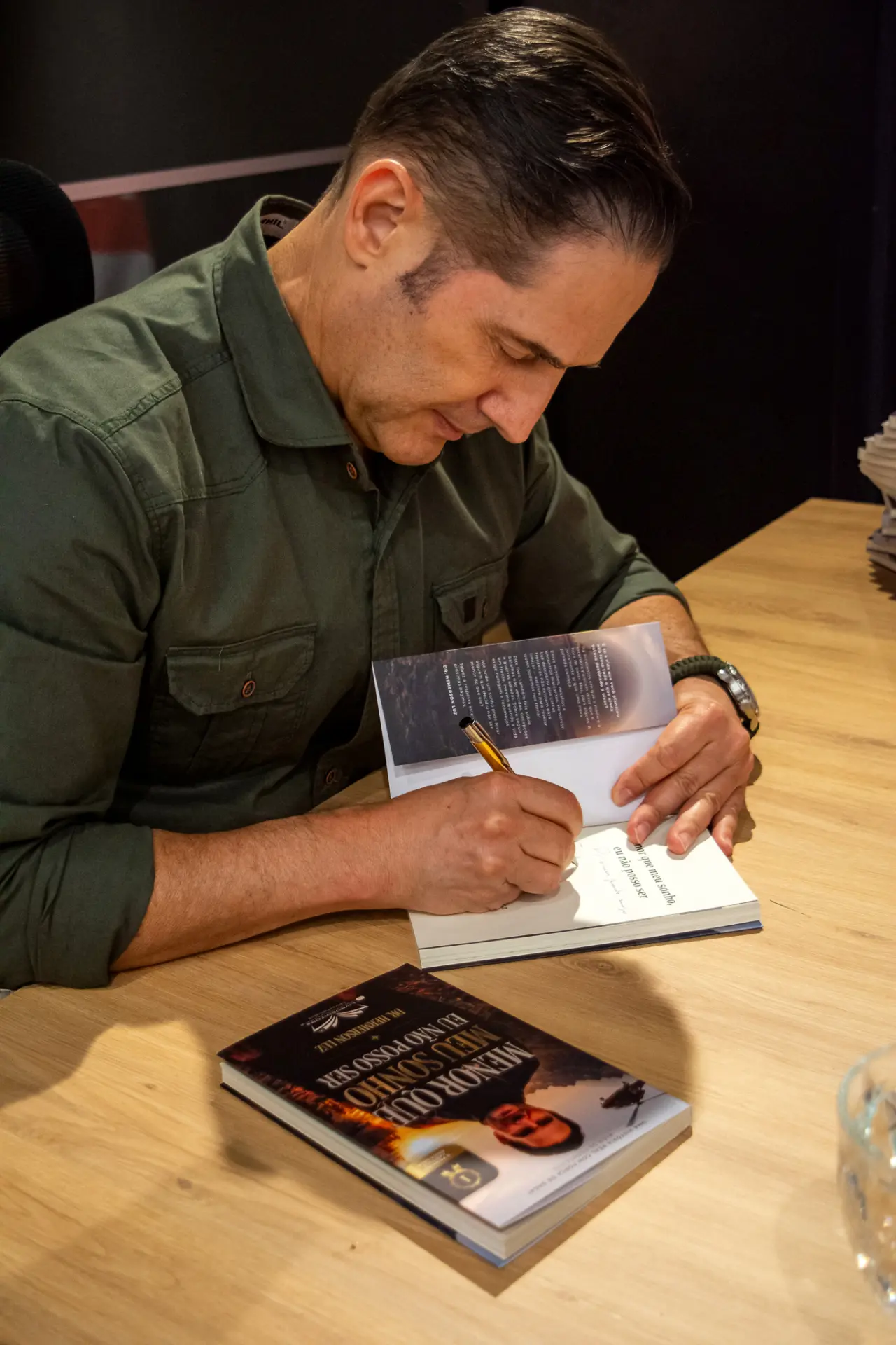 Dr. Hemerson Luz assinando seu livro Menor que meu sonho, eu não posso ser em lançamento.