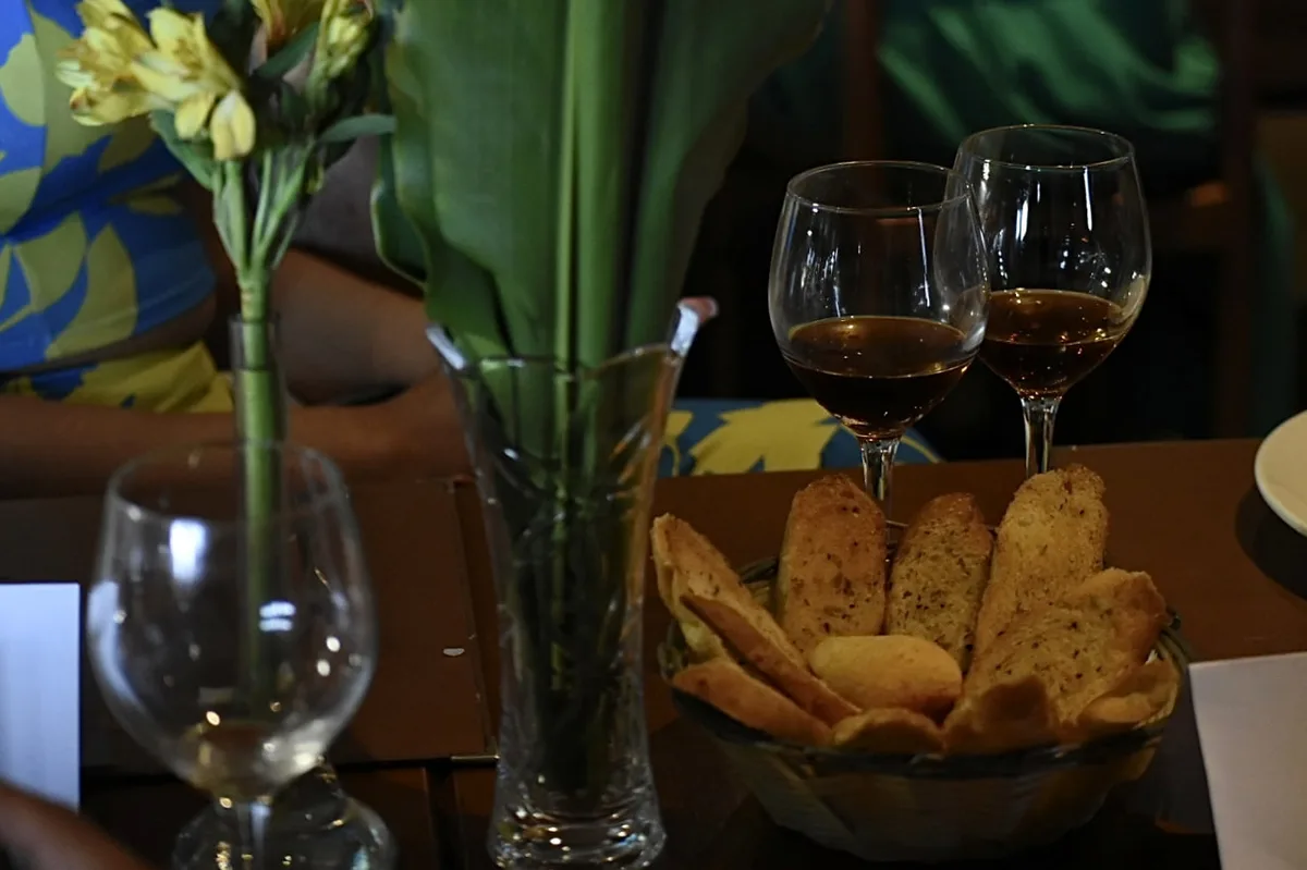 Mesa do evento com pães, vinho e arranjo de flores