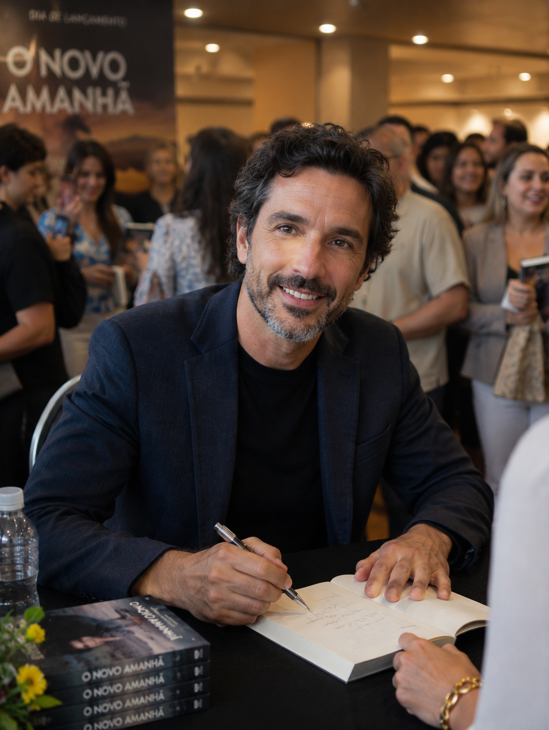 Autor sorrindo enquanto autografa seu livro publicado em noite de lançamento