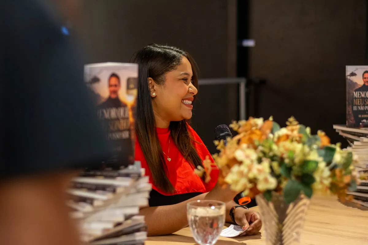 Autor sorrindo enquanto autografa seu livro publicado em noite de lançamento